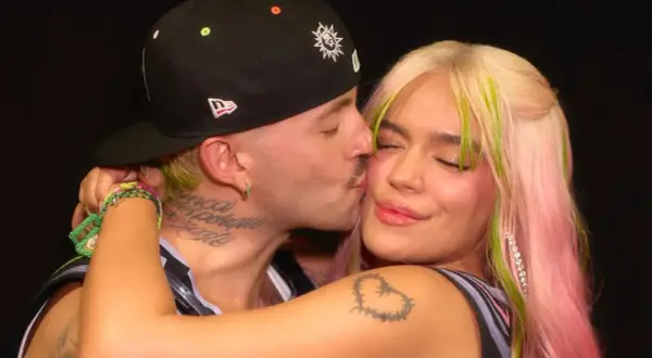Feid le da un tierno beso a Karol G, capturando un momento íntimo entre los artistas.
