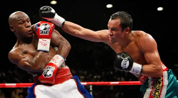 Boxer dodges a punch with a shoulder roll, his opponent's glove narrowly missing his head.