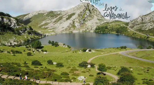 Un perro disfruta de la ruta circular por los lagos de Covadonga, con un paisaje montañoso y un lago sereno.