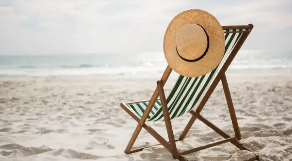 Pusta leżanka z kapeluszem na plaży, idealna na węgry wakacje. Słońce odbija się w wodzie, zapraszając do relaksu.