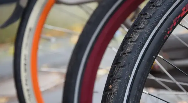 Zbliżenie na opony rowerowe 29 cali z widocznymi bieżnikami i obręczami w różnych kolorach.
