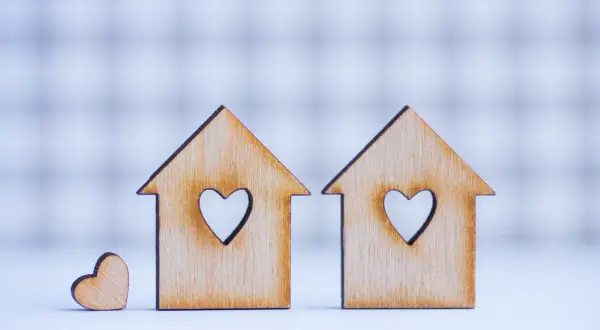 Due casette di legno con cuori intagliati, una più piccola accanto. Simboleggiano la casa e l'amore, ma anche i potenziali conflitti legati ai lavori senza consenso comproprietari.
