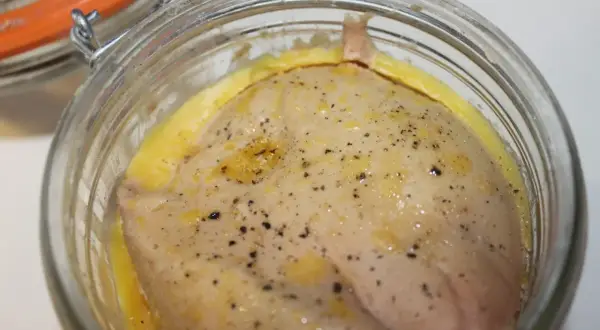 Foie gras cru assaisonné, prêt pour la recette du parfait. Un délice en préparation dans un bocal en verre.