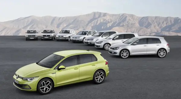 Evolución de los modelos Golf por años, desde el clásico hasta el moderno verde lima, alineados ante un paisaje montañoso.