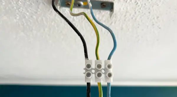 Drei Kabel (schwarz, grün-gelb, blau) sind mit einer Klemme verbunden, bereit zum Lampe abmontieren.