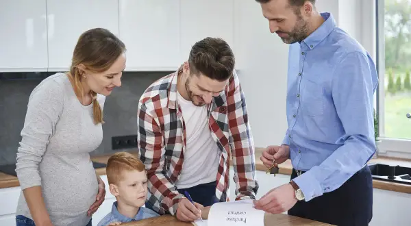 Familia firma contrato de compraventa. El agente inmobiliario les explica que es legal pedir aval para un alquiler.