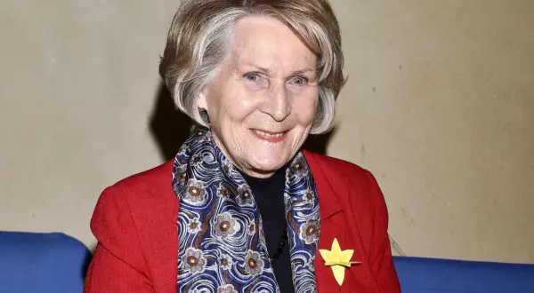 Uśmiechnięta Irena Santor w czerwonej marynarce i wzorzystym szalu. Wiele osób zastanawia się, ile lat ma Irena Santor, a jej wygląd świadczy o witalności.