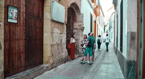 Un grupo de turistas pasea por una calle estrecha y empedrada del quartier juif de Cordoue, admirando la arquitectura antigua.