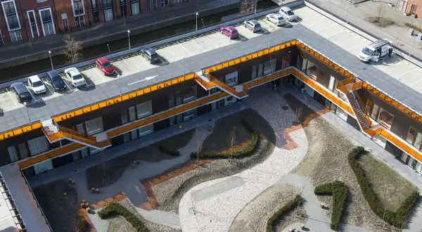 Moderne Architektur mit begrüntem Innenhof und Parkplätzen. Die Dachpappe wurde begehbar gemacht und dient als Parkfläche.