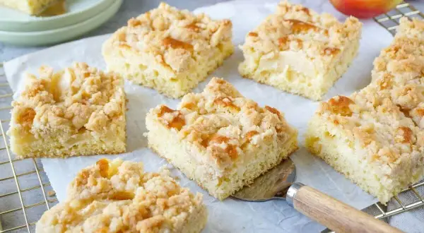 Saftiger Apfelkuchen mit Streuseln, frisch gebacken und in Stücke geschnitten. Ein Genuss für jeden Kaffeetisch.