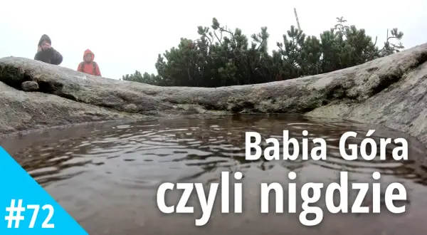 Mglisty dzień na Babiej Górze. Dwie osoby w kurtkach przeciwdeszczowych stoją za kamieniem, obok kałuży.