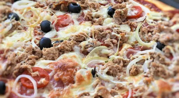 Pyszna pizza z tuńczykiem, oliwkami, cebulą i pomidorami, obficie posypana serem. Idealna na szybki obiad.