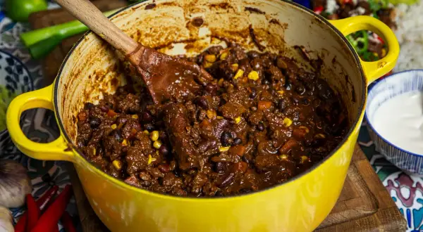 En stor gul gryta fylld med mustig chili sin carne, redo att serveras. Perfekt för ett värmande recept.