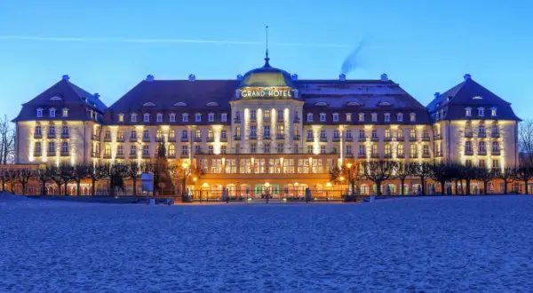 Grand Hotel w Sopocie, jeden z najpiękniejszych hoteli w Polsce, lśni nocą nad piaszczystą plażą.