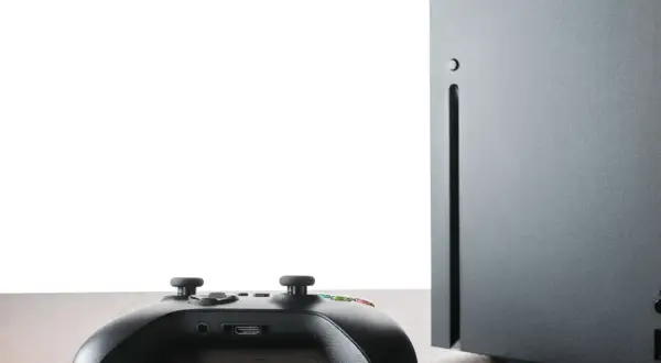Czarny kontroler Xbox i konsola Series X na drewnianym blacie. Czy gry z Xbox 360 działają na Xbox Series X? Sprawdźmy!