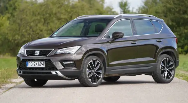 Brązowy Seat Ateca na drodze, z widocznymi felgami i detalami nadwozia. Poznaj jego wymiary.