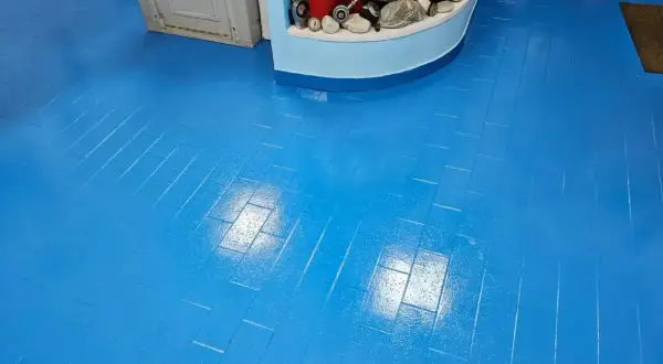 Pavimento in resina blu brillante sopra piastrelle, con riflessi luminosi che creano un effetto dinamico.