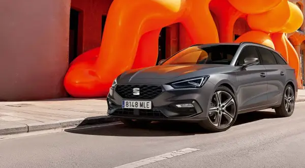 Grå Seat Leon Sportstourer parkerad framför en orange skulptur. En perfekt bil för en seat leon sportstourer test.