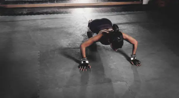 Femme en position de pompe, travaillant ses bras et son dos. Un exercice efficace pour tonifier le corps et réduire le bourrelet aisselle.