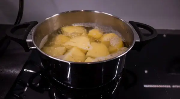 Gotowane ziemniaki w garnku, gotowe do przygotowania pysznej sałatki ziemniaczanej.