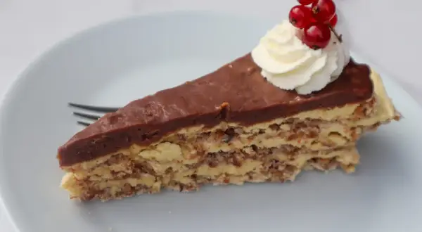 En bit chokladtårta med mandelbotten, grädde och vinbär. Ett perfekt recept på daimtårta med mandelbotten.
