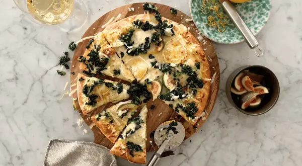 En härlig pizza med grönkål och fikon, perfekt som middagstips helg. Serveras med ett glas vitt vin och citronzest.