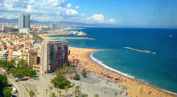 Słoneczna plaża Barceloneta tętni życiem. Tłumy ludzi odpoczywają na piasku, a błękitne morze zaprasza do kąpieli.
