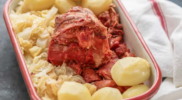 Un plato de botillo, con repollo, patatas y trozos de carne roja.