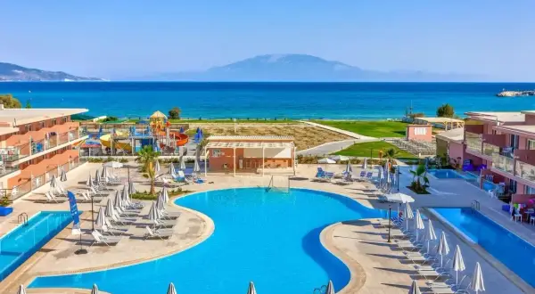 Słoneczny dzień w Alykanas Beach Hotel. Baseny, zjeżdżalnie wodne i leżaki czekają na gości. W tle błękitne morze i góry.
