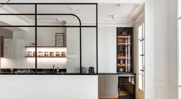 Elegante cocina semiabierta cristal con estantes iluminados, vitrina y vinoteca. Un espacio moderno y funcional.