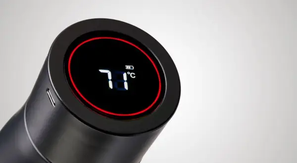 Schwarze Trinkflasche mit digitaler Anzeige (71°C) und Akku-Symbol. Eine smarte Trinkflasche mit Erinnerungsfunktion, die die Temperatur anzeigt.