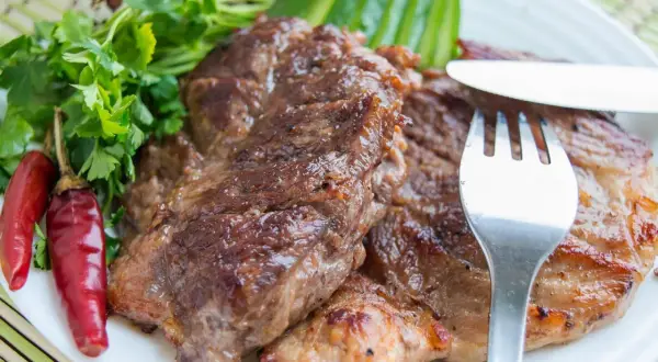 Saftiges Schweinesteak, mariniert und perfekt gegrillt, serviert mit Petersilie, Chilischoten und Wachteleiern. Ein Genuss für Fleischliebhaber.