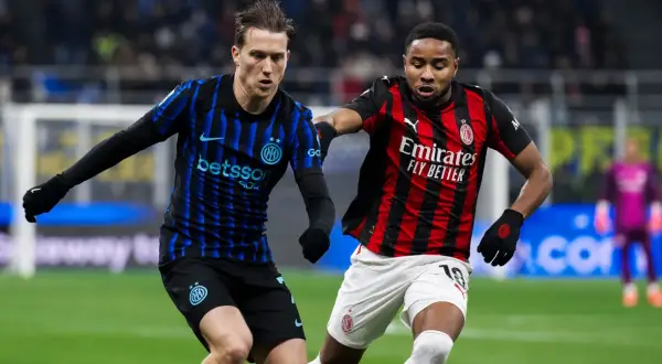 Piłkarze Interu i AC Milan, słynnego klubu piłkarskiego z Mediolanu, walczą o piłkę na boisku.