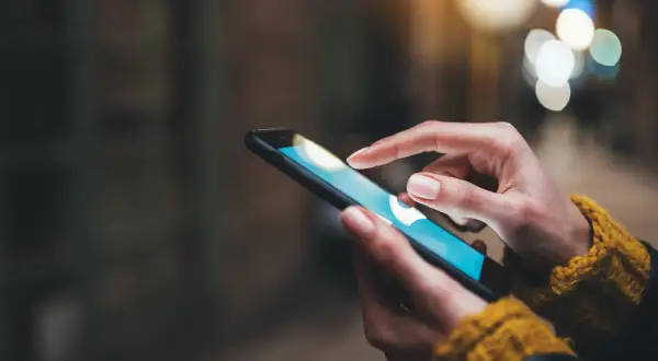 Dłoń dotyka ekranu smartfona, szukając informacji, jak wyczyścić schowek w telefonie.
