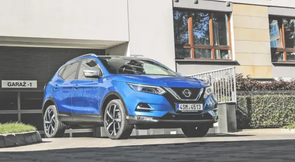 Niebieski Nissan Qashqai 1 parkuje przed garażem.