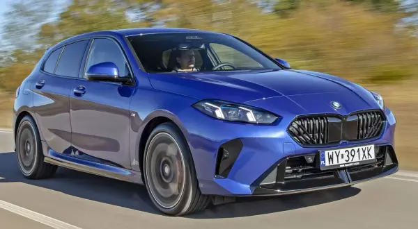 Niebieskie BMW Seria 1 pędzi po drodze, kierowca skupiony na trasie.