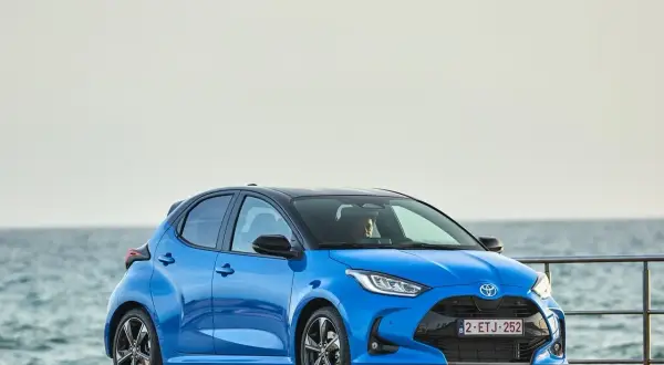 Niebieski segment a, Toyota Yaris, stoi przy morzu.