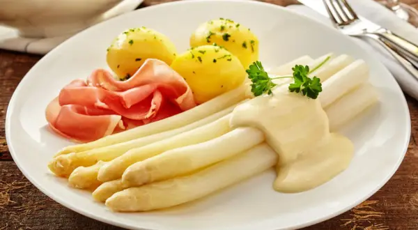 Spargel mit Sauce Hollandaise, Salzkartoffeln und Schinken. Die Menge der Sauce pro Person ist großzügig bemessen.