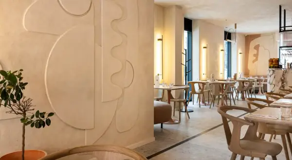Nowoczesne wnętrze restauracji z dekoracyjnymi tynkami glinianymi na ścianach, geometrycznymi formami i minimalistycznymi meblami.