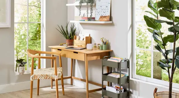 Bright, airy desk setup with plants and a rolling cart. Great small office decor ideas for a productive workspace.