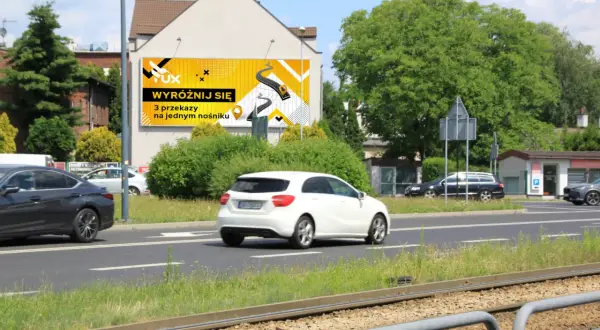 Reklama na ogrodzeniu przepisy: "Wyróżnij się 3 przekazy na jednym nośniku". Jasnożółte tło z grafiką drogi i ikonami.