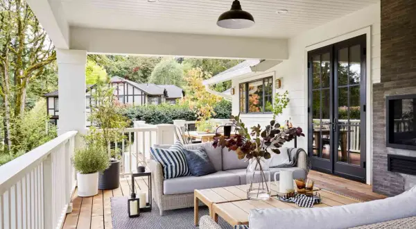 Cozy backyard makeover with a covered porch, outdoor sofa, coffee table, and fireplace.