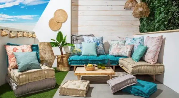 Acogedora zona chill out interior con cojines coloridos, suelo de césped artificial y luces de estilo bohemio.
