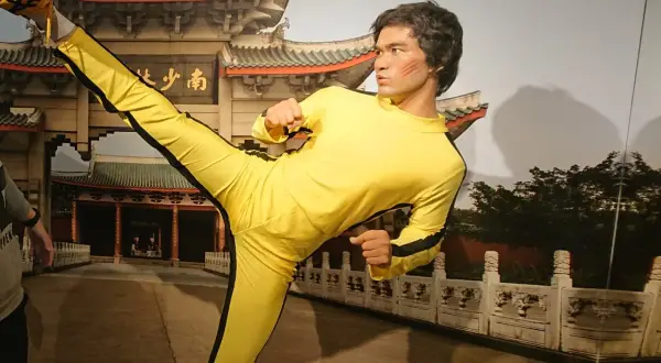 Bruce Lee w żółtym dresie wykonuje kopnięcie w powietrzu. Figura wosku w muzeum figur woskowych w Jastrzębiej Górze.
