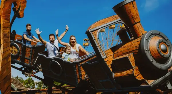 Rodzina na drewnianym rollercoasterze, który wygląda jak lokomotywa. To jeden z największych rollercoasterów w Europie, zapewniający mnóstwo emocji.
