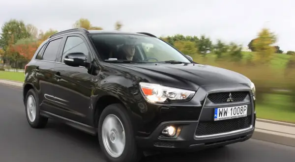 Czarny Mitsubishi ASX 1.6 benzyna w ruchu, z kierowcą za kierownicą.