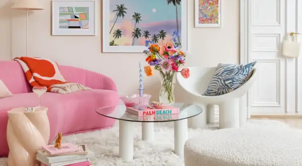 Ein Wohnzimmer im **danish pastel** Stil mit pinkem Sofa, bunten Blumen und Kunstwerken.