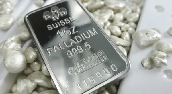 Sztabka palladu 1 uncja 999,5 na tle luźnych granulek tego cennego metalu.