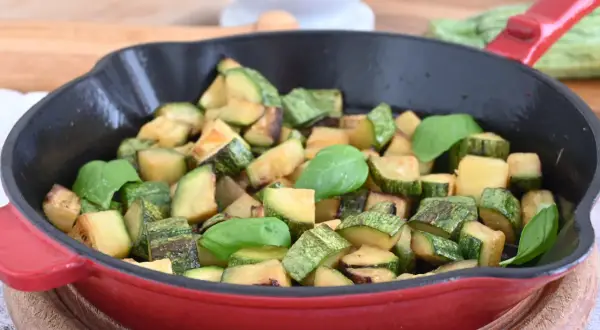 Zucchine in padella sfiziose, dorate e profumate, guarnite con foglie di basilico fresco. Un contorno semplice e gustoso.