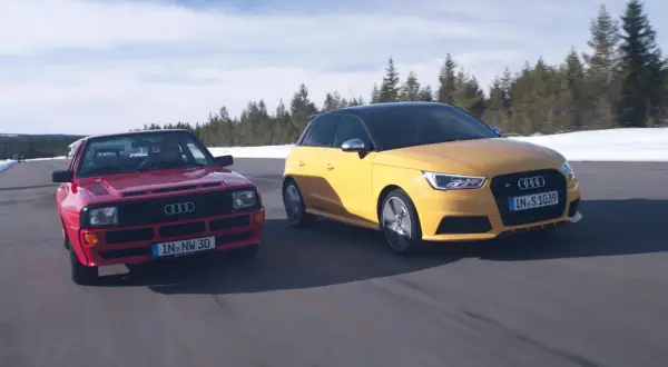 Dwa Audi S1 Quattro, czerwony klasyk i żółty współczesny, pędzą po drodze wśród zimowych krajobrazów.